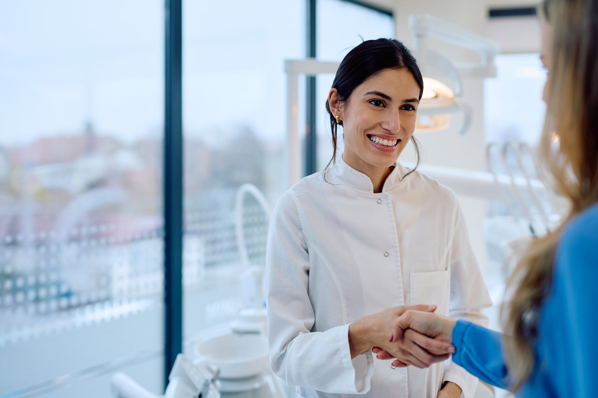 Dental professional shaking hand with patient in clinic