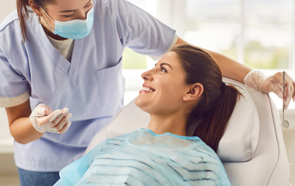 Doctor dentist, nurse, or orthodontist conducting a dental examination for a smiling patient in the hospital office. Focused on providing oral care and ensuring dental health in the dentistry clinic.